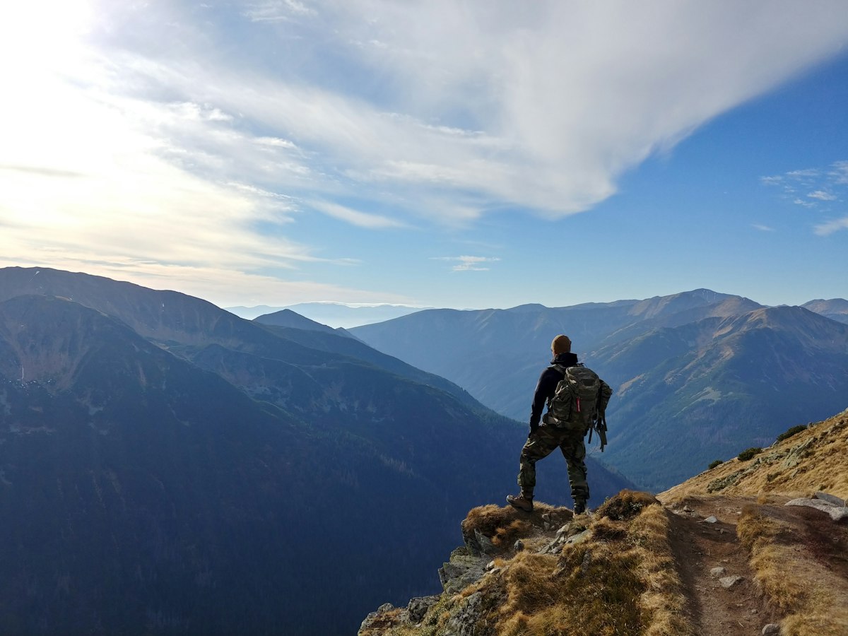 Homem no alto de uma montanha sob o céu azul